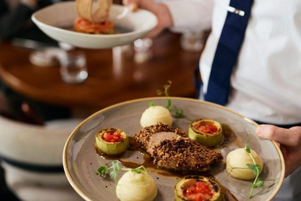 Close up of waiter serving a dish in a restaurant.