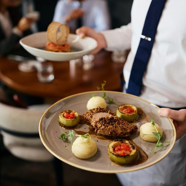 Close up of waiter serving a dish in a restaurant.