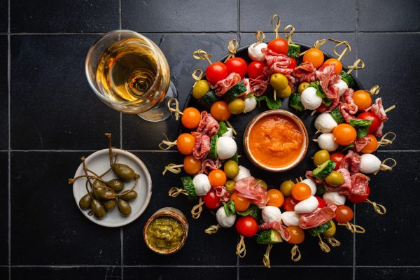 Appetizer and refreshment set. Plate of canapes with vegetables, cheese, salami and olives decorated for party table, top view